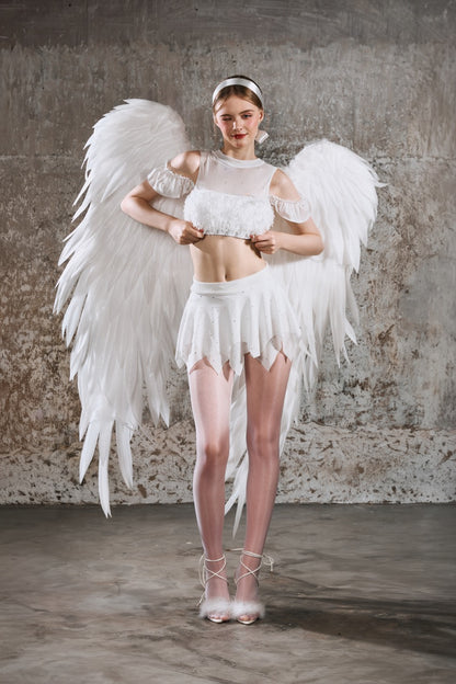 Person wearing an angel costume with white wings against a textured wall Hebe design by Spincess Aerial Pole Dance Wear Ballet Barre